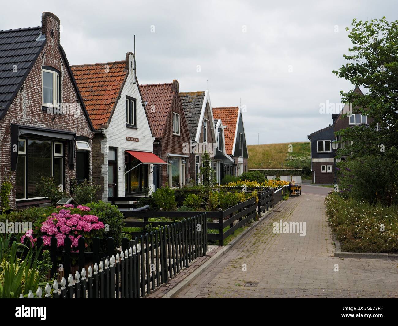 Pequeñas casas tradicionales holandesas detrás del dique en Oudeschild en la isla de Texel, Holanda Foto de stock