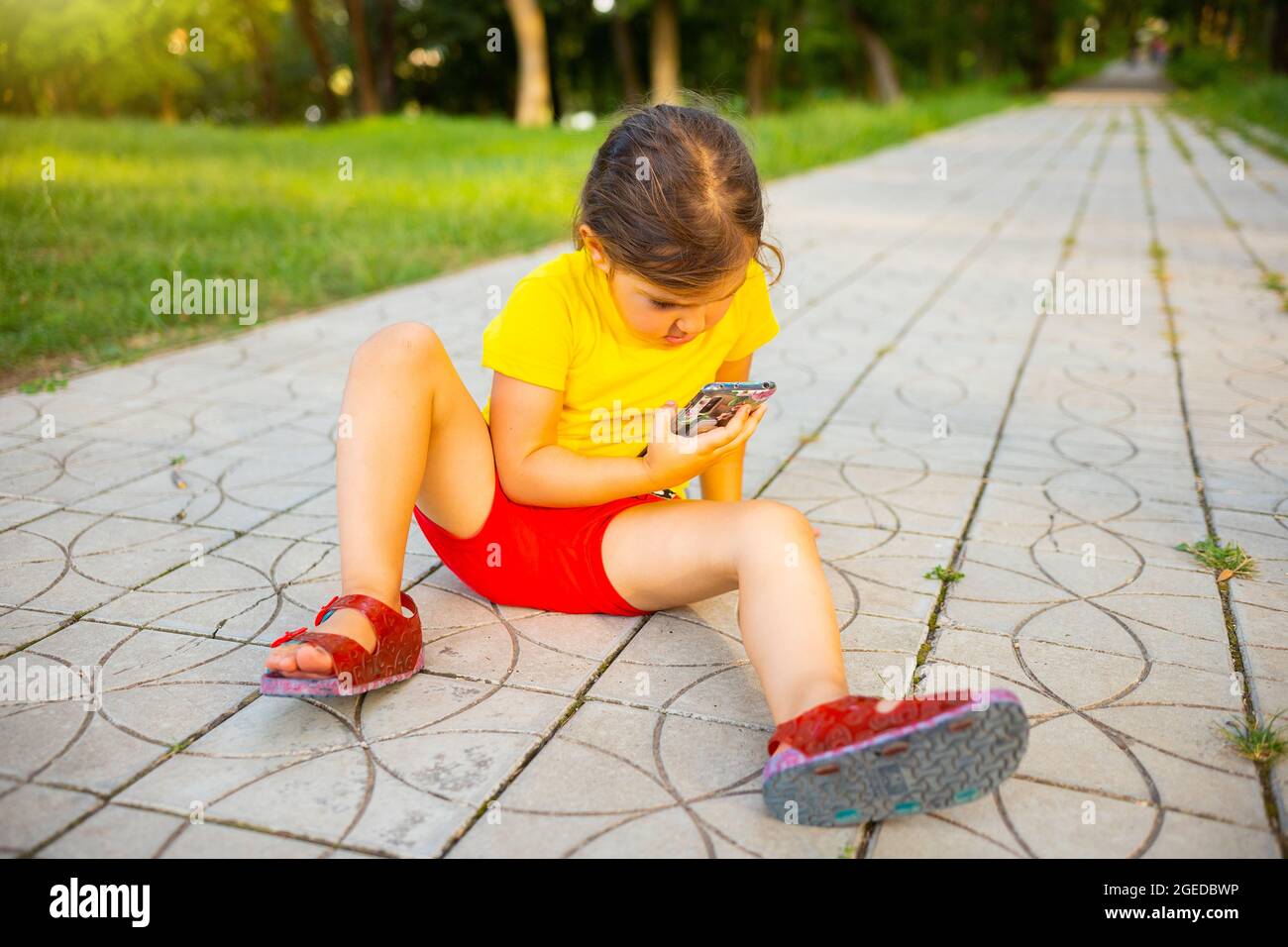 Linda niña pequeña con una camiseta amarilla y coloridos leggings se sienta  en el suelo sosteniendo un gran lollipop en la mano y sonríe Fotografía de  stock - Alamy
