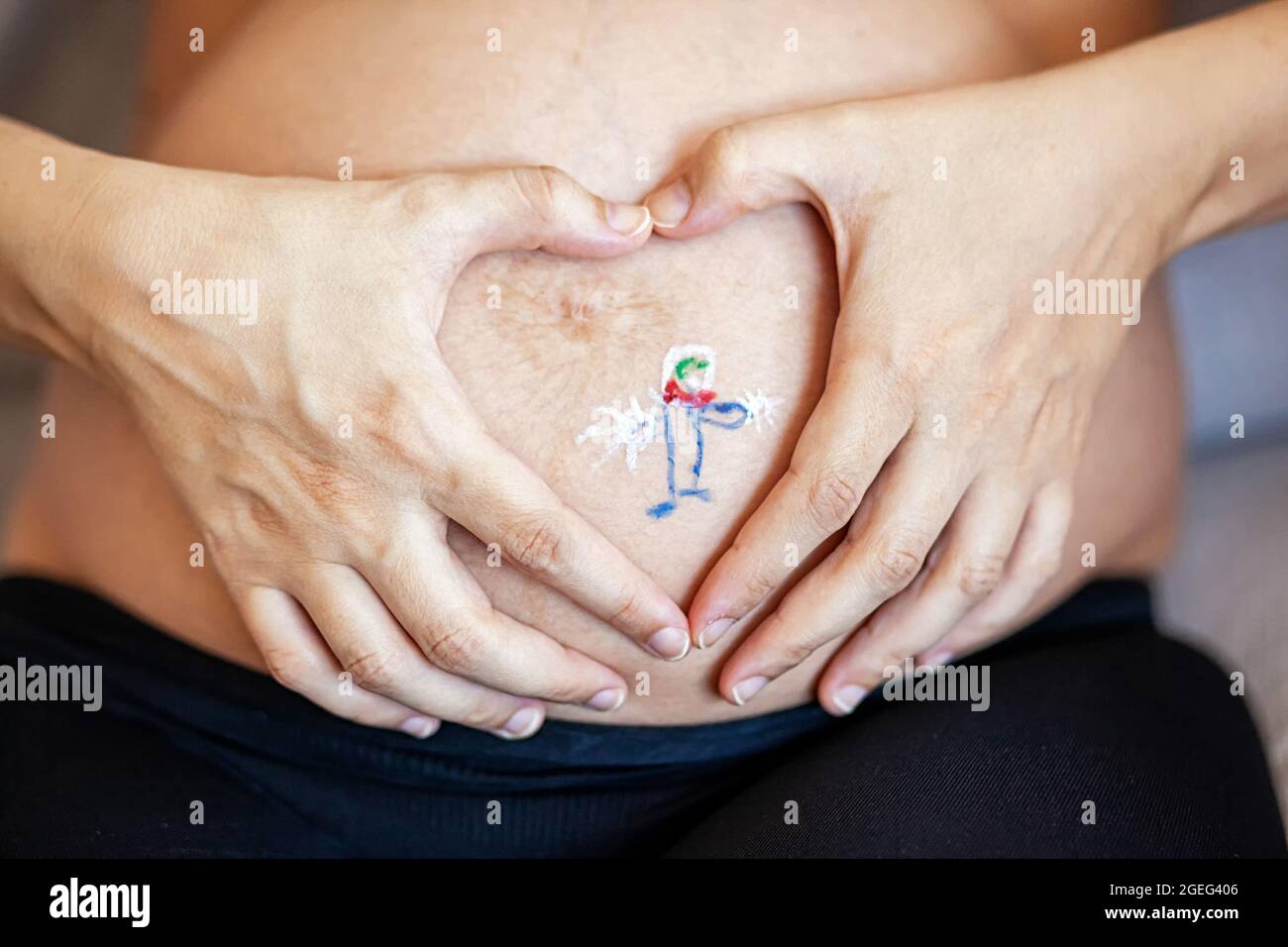 Artista de pintura corporal pintando sobre el vientre de una mujer  embarazada