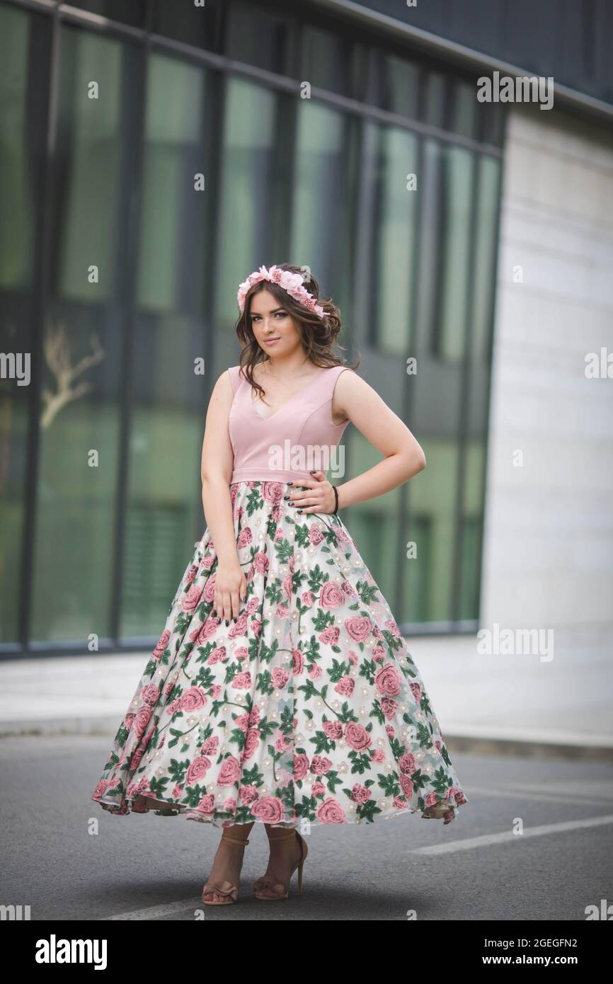 Chica joven bonita con un vestido rosa con un estampado de flores en los s  Fotografía de stock - Alamy