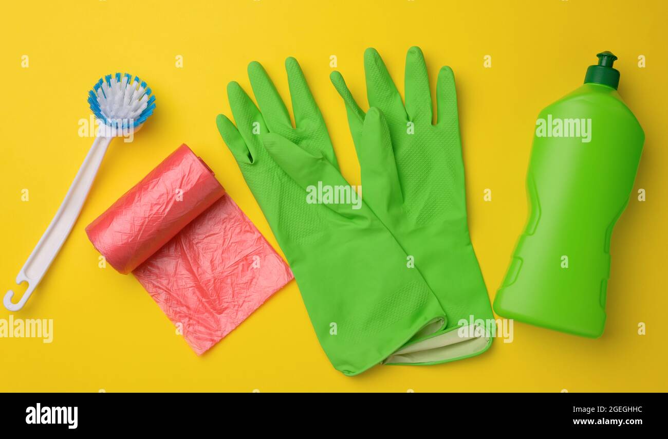 guantes verdes de goma para limpieza, bote de basura rojo, rollo de bolsa  de plástico y botella de plástico con detergente sobre fondo amarillo, set,  vista superior Fotografía de stock - Alamy