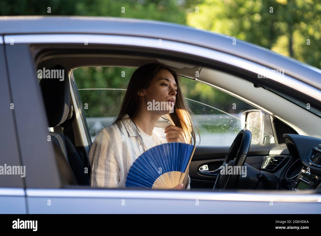 Chica conductor con ventilador de mano que sufre de calor en el coche,  tiene problemas con el aire acondicionado que no funciona Fotografía de  stock - Alamy