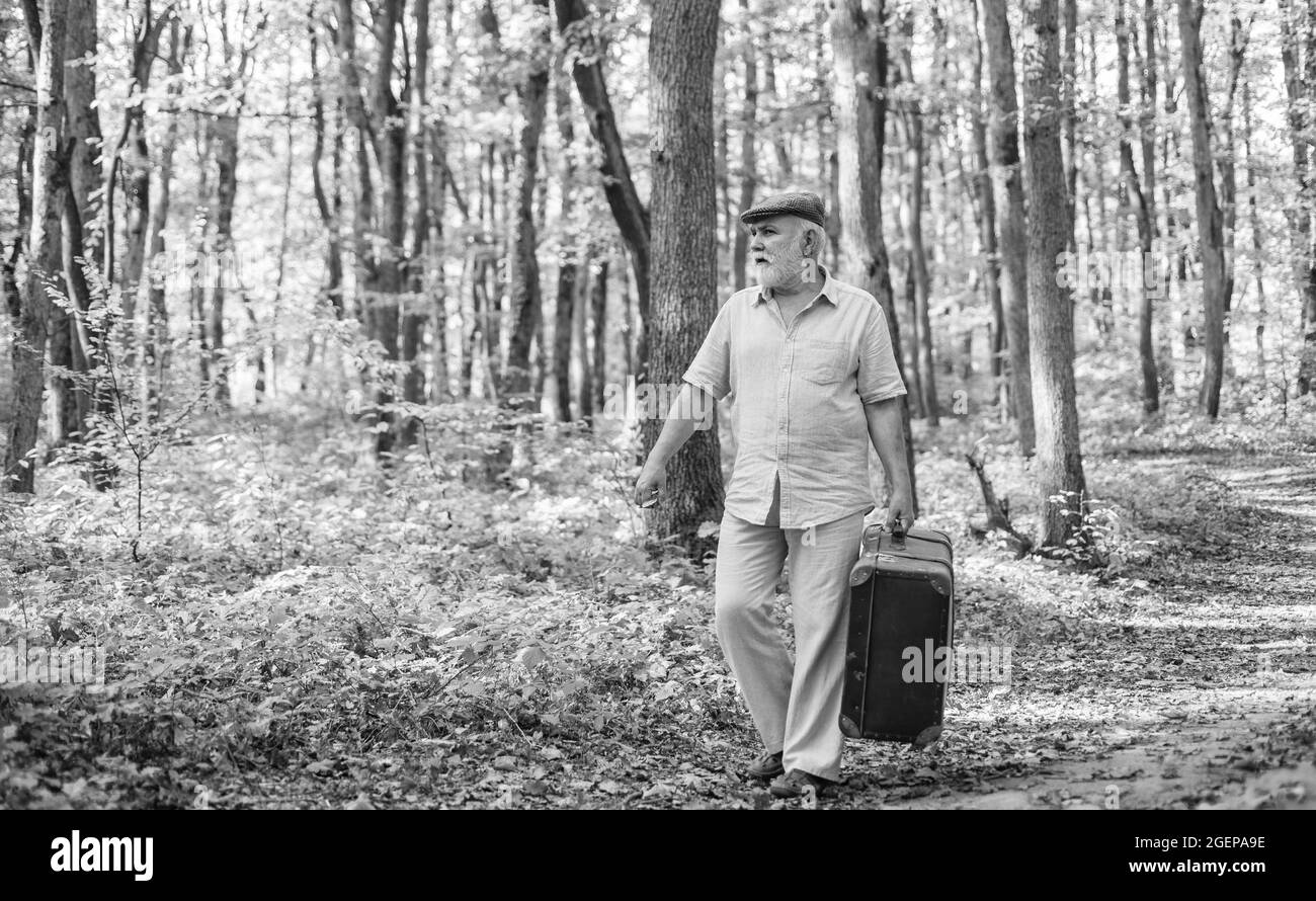 Abuelo con maleta vintage en la naturaleza. Unidos con la naturaleza. Fin de semana en la naturaleza. Ancianos. Vacaciones y relax. Concepto de jubilación. Hombre maduro Foto de stock