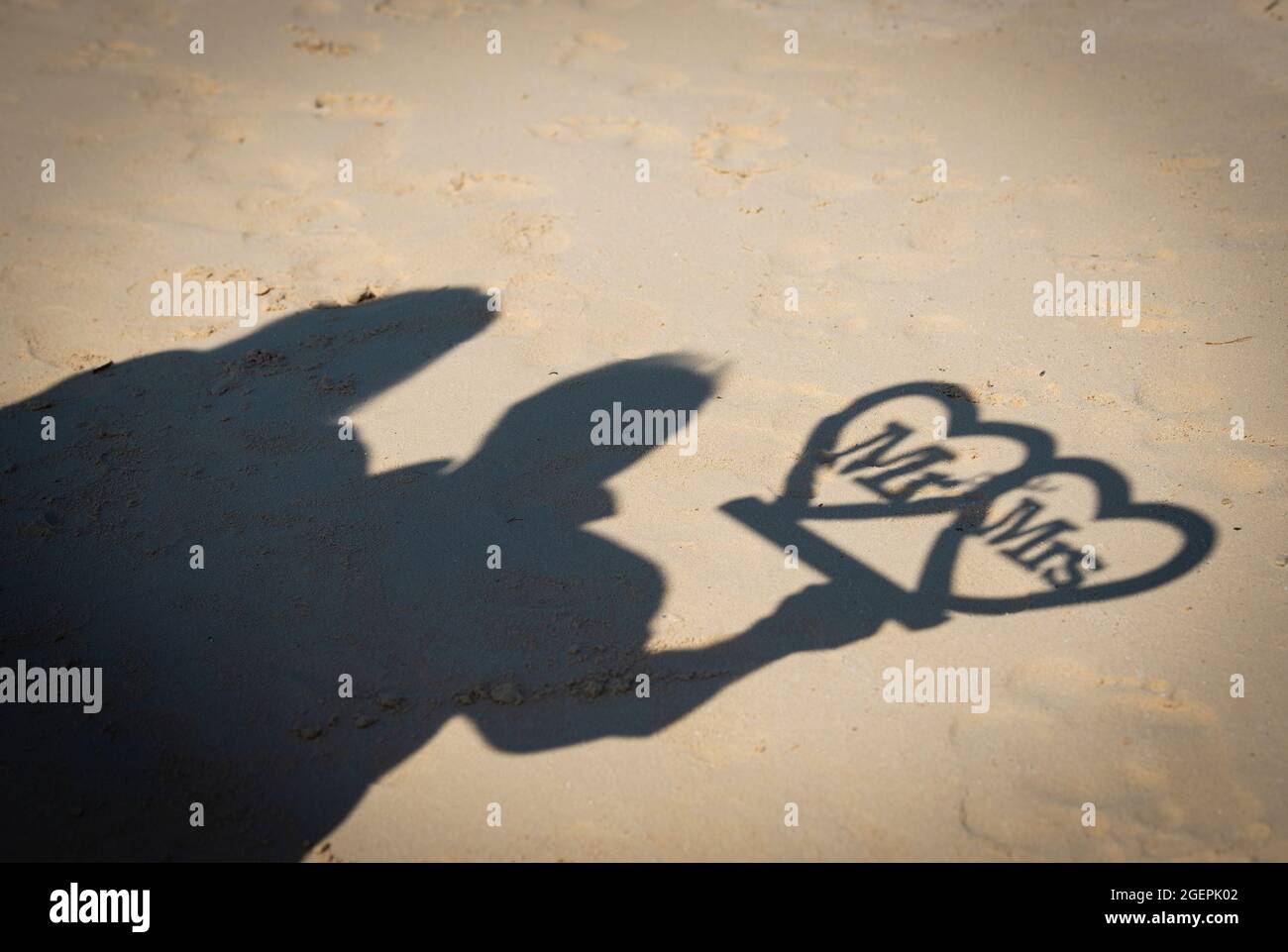 Silueta abstracta sombra en la playa de arena de la pareja sosteniendo el signo de mr y mrs el día de la boda Foto de stock