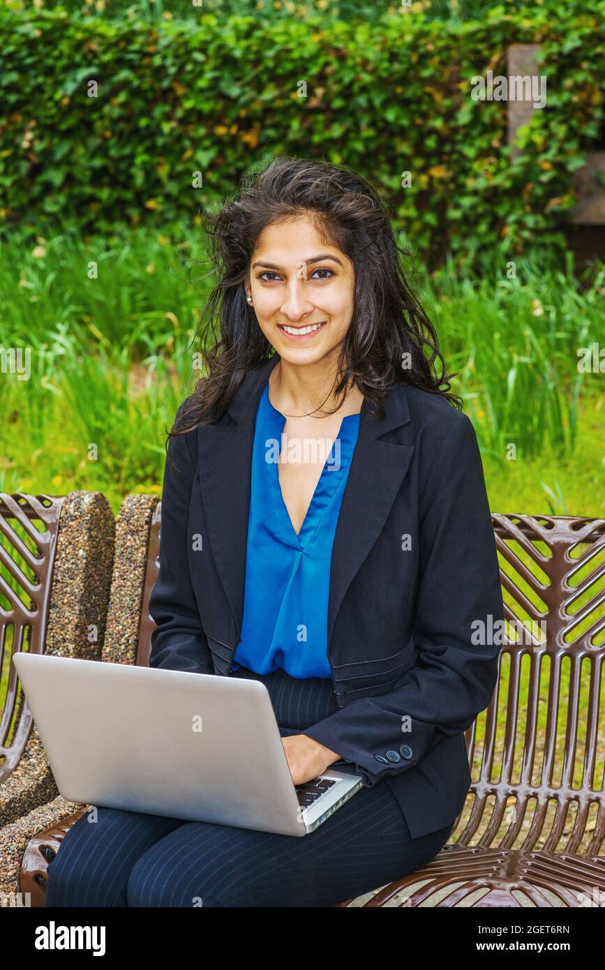 Disparo vertical de una mujer india con un blazer negro con una camiseta  azul sentado en un banco Fotografía de stock - Alamy