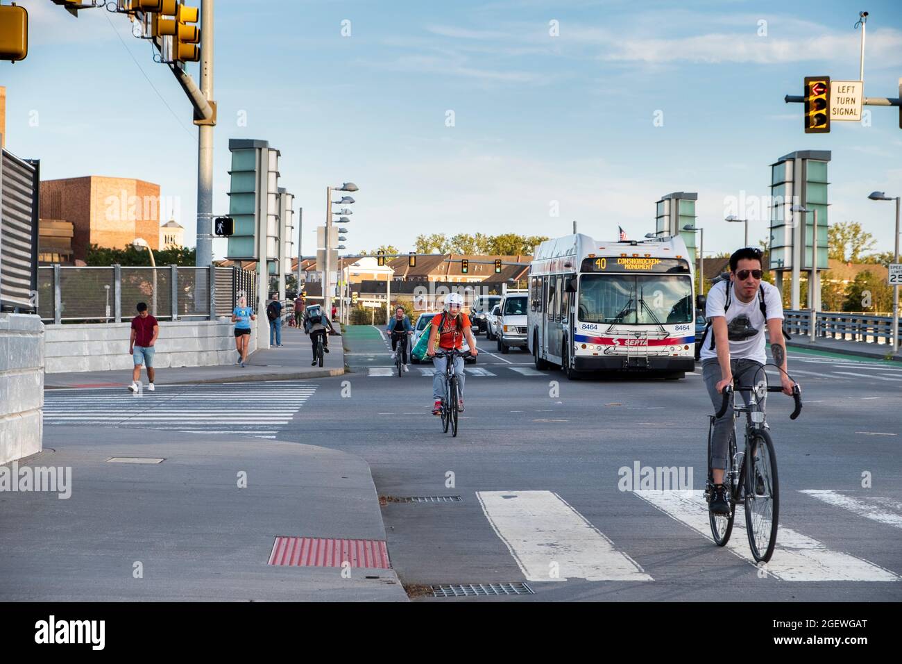 Ciclistas que se desplazan por las calles de la ciudad carriles para bicicletas con coches y tráfico, University City, Philadelphia, Pennsylvania, USA Foto de stock