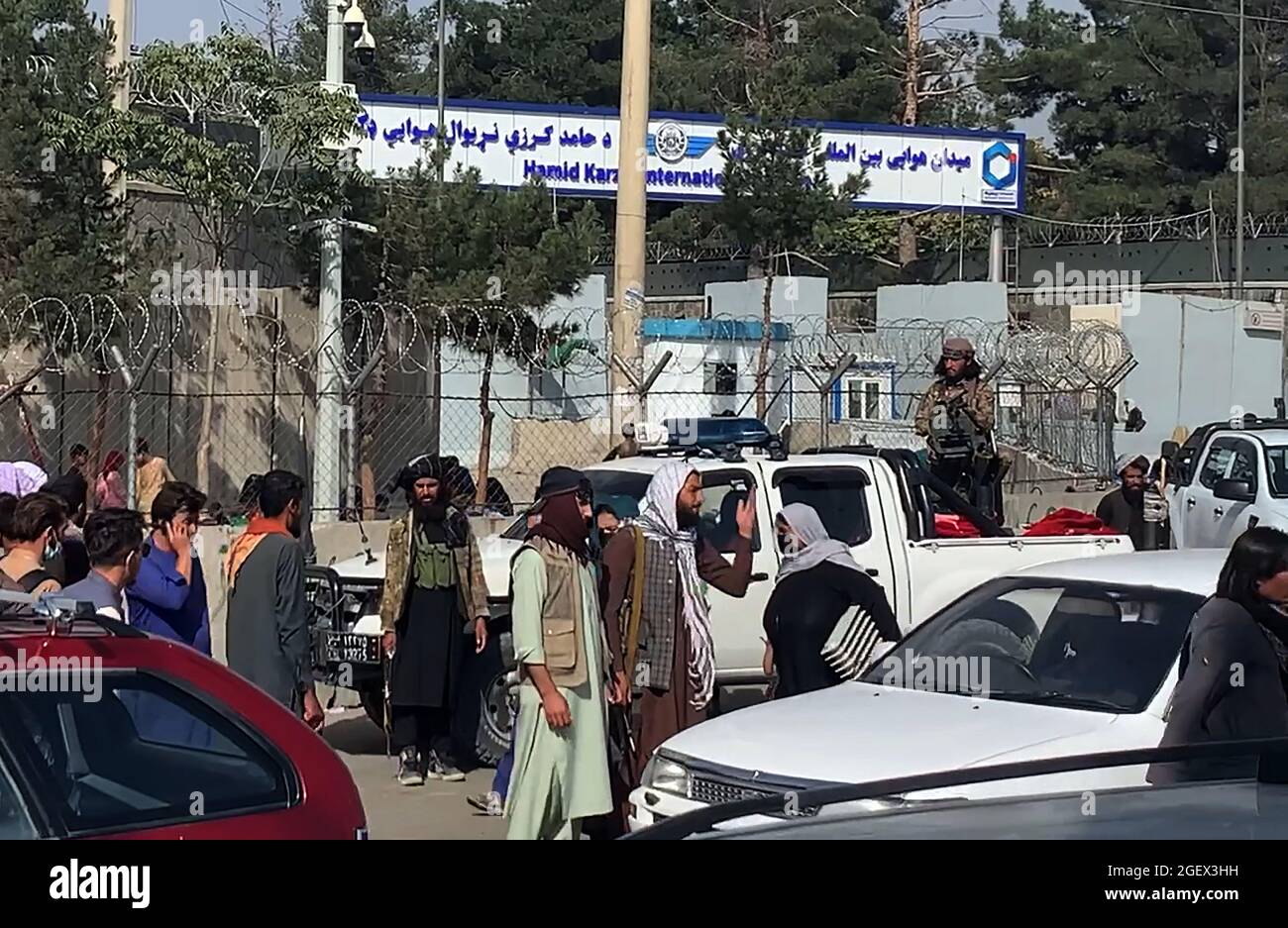 Kabul, Afganistán. 21st de agosto de 2021. Combatientes talibanes vigilan mientras los afganos se reúnen fuera del aeropuerto internacional Hamid Karzai para huir del país, en Kabul, Afganistán, el sábado 21 de agosto, 2021. Foto de Bashir Darwish/ Crédito: UPI/Alamy Live News Foto de stock