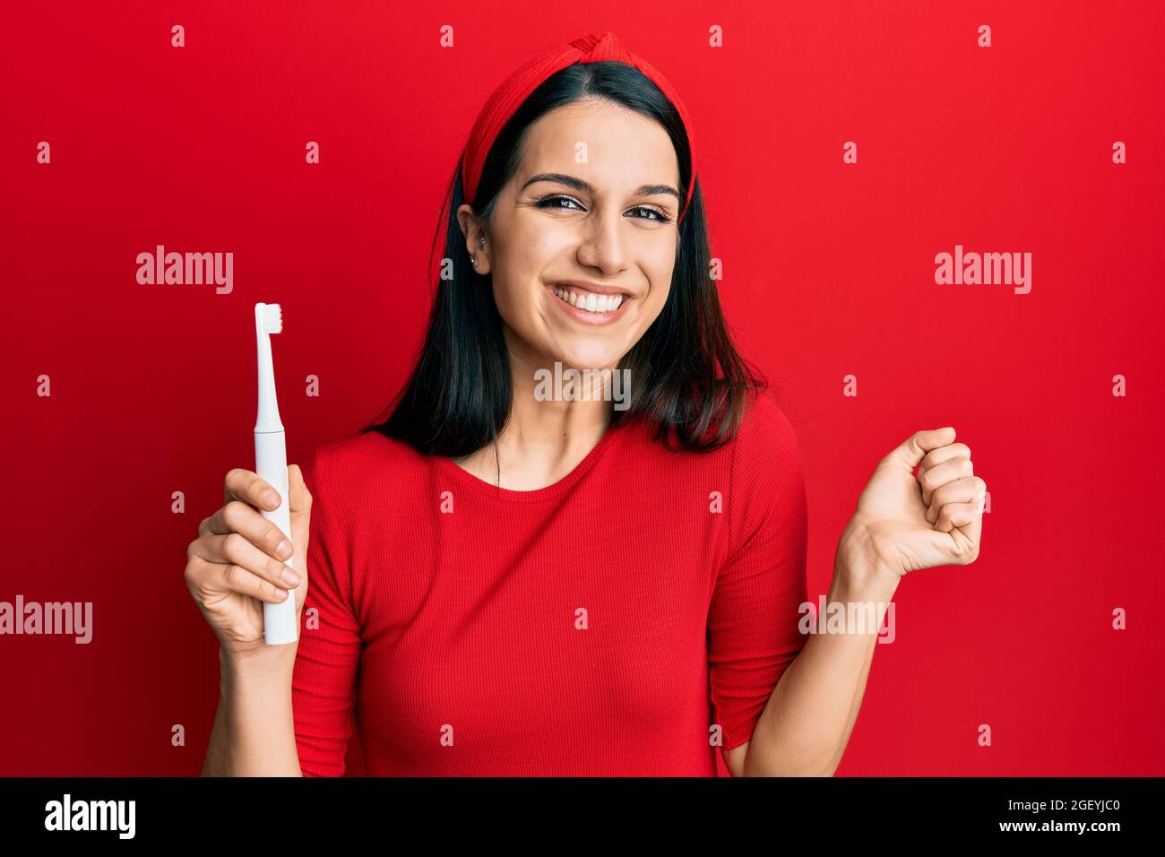 Joven mujer hispana sosteniendo un cepillo de dientes eléctrico gritando  orgullosa, celebrando la victoria y el éxito muy emocionado con el brazo  levantado Fotografía de stock - Alamy