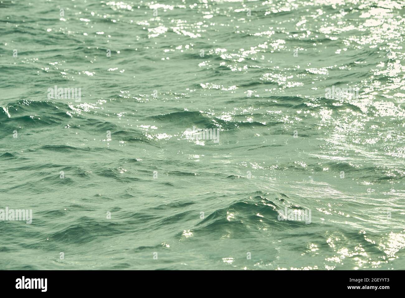 Detalle de la luz del sol que se refleja en el brillante mar. Gorrión en el agua - fondo. Agua del mar con el resplandor del sol y la ondulación. Naturaleza poderosa y pacífica c Foto de stock