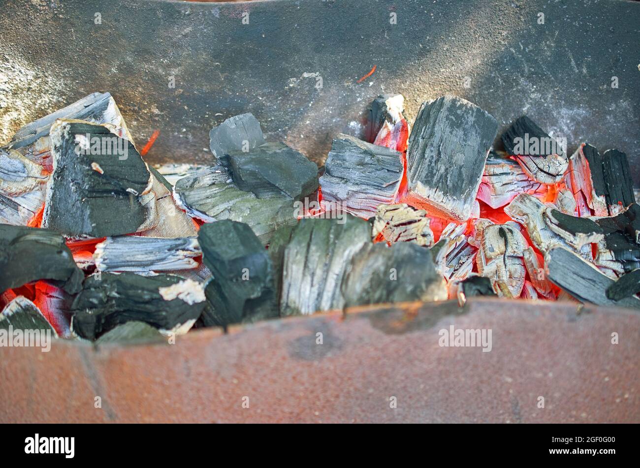 Los carbones rojos-calientes se están esmoldeando en una parrilla de metal vieja. Foto de stock