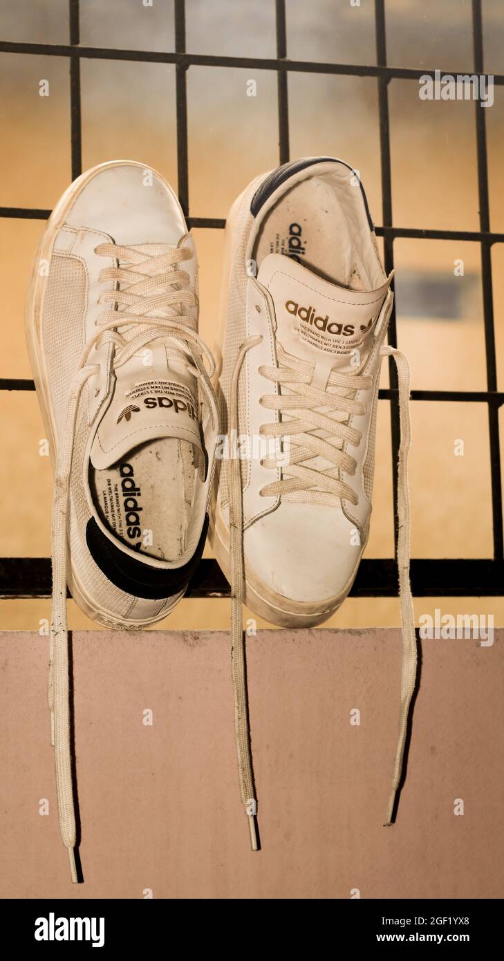 Modernos zapatos blancos y dorados Adidas originales Stan smith llenos de  polvo que se mantienen inclinados a las rejillas Fotografía de stock - Alamy