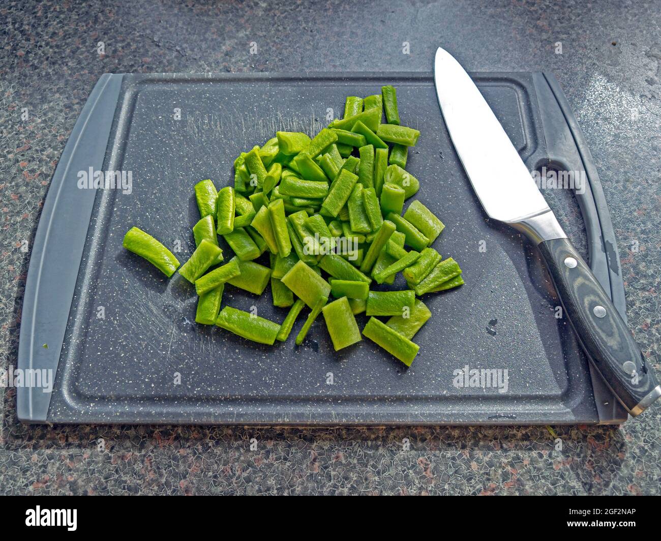 Granos de colada picados con un cuchillo de chef en una tabla de cortar Foto de stock