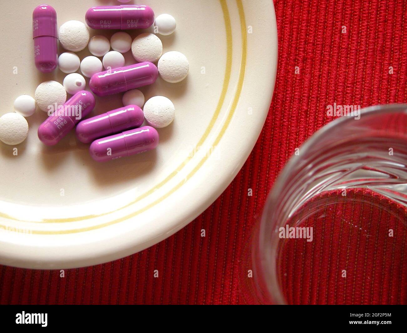 pastillas en un plato y vaso de agua, adicción a las pastillas Foto de stock