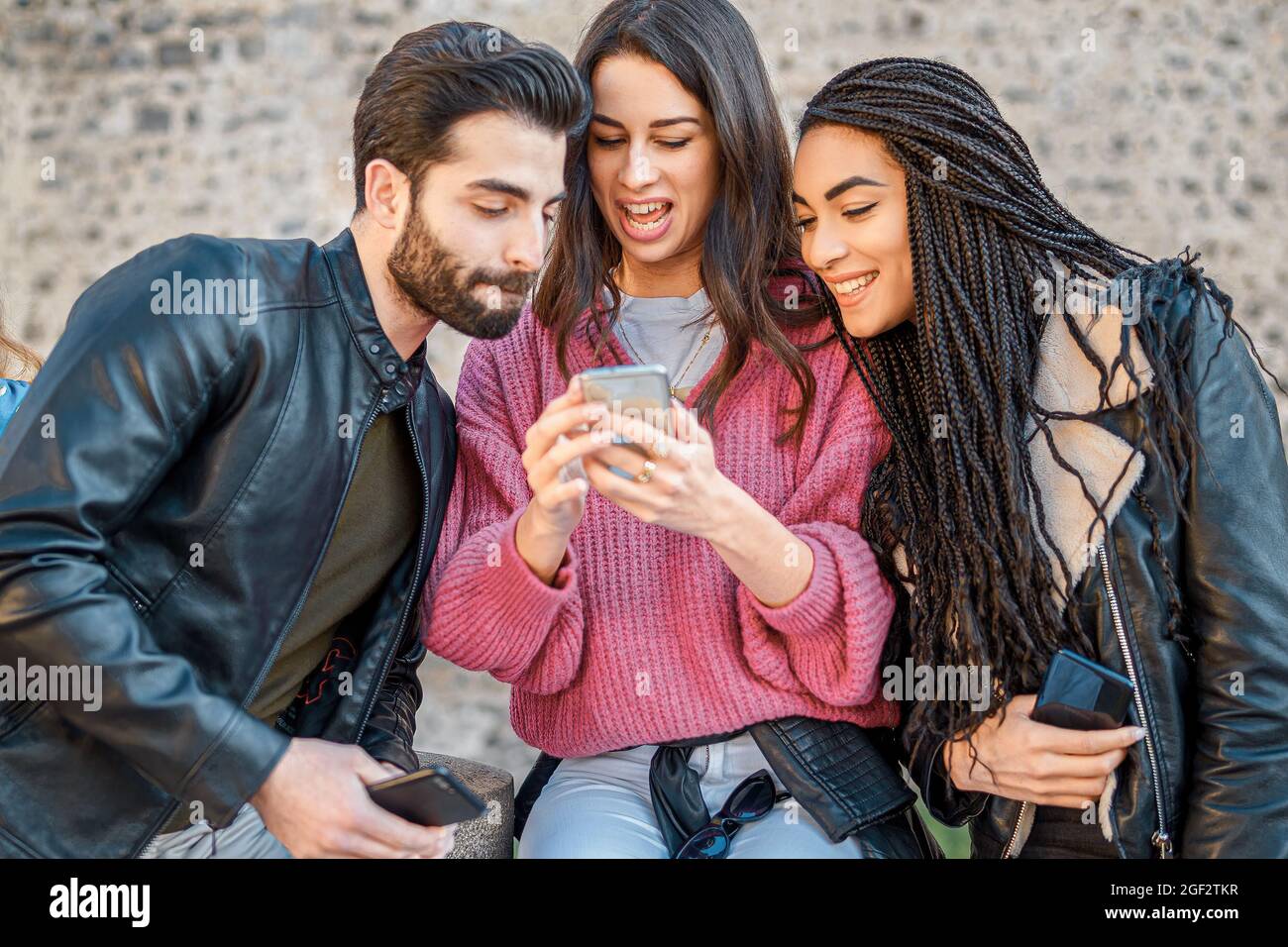 Generación z jóvenes navegando contenido de redes sociales en línea con un smartphone. Zoomers que utilizan la tecnología del teléfono juntos al aire libre. Foto de stock