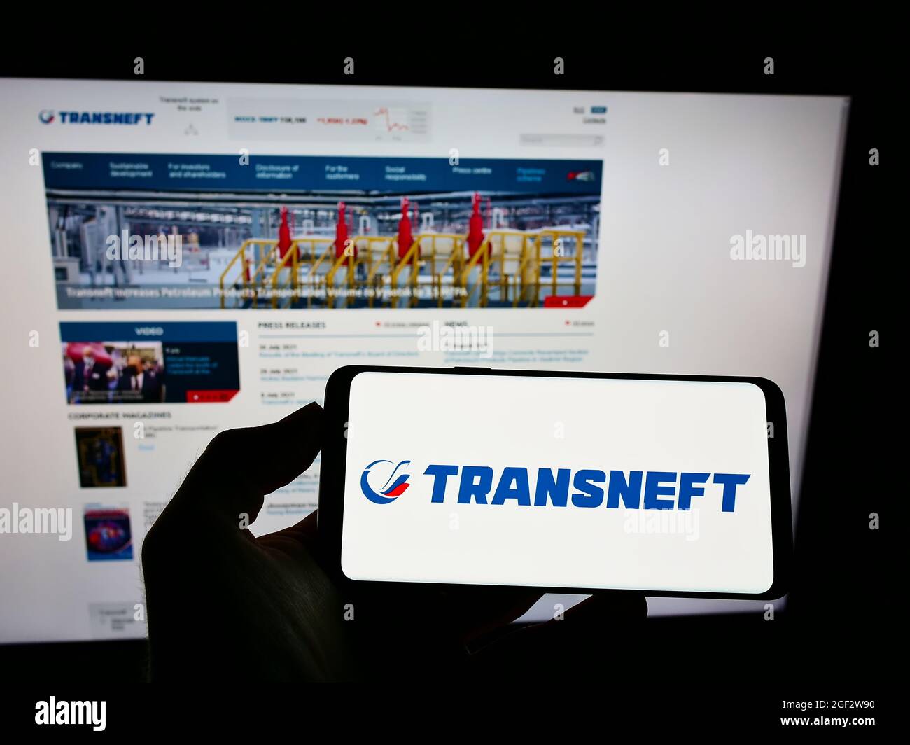 Persona que sostiene el teléfono móvil con el logotipo de la compañía rusa de tuberías Transneft JSC en la pantalla frente a la página web del negocio. Enfoque en la pantalla del teléfono. Foto de stock