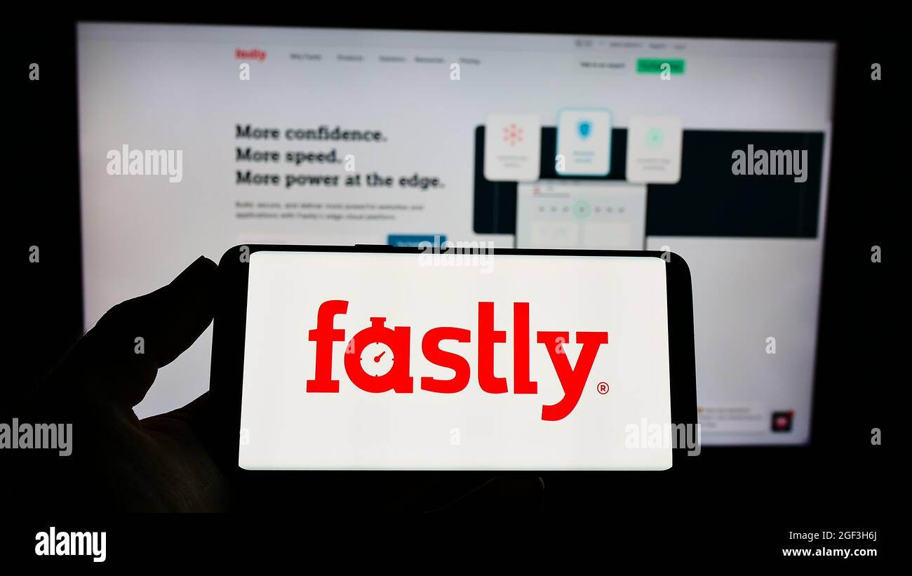Persona que sostiene un smartphone con el logotipo de la empresa estadounidense de cloud computing Fastly Inc. En la pantalla delante del sitio web. Enfoque en la pantalla del teléfono. Foto de stock