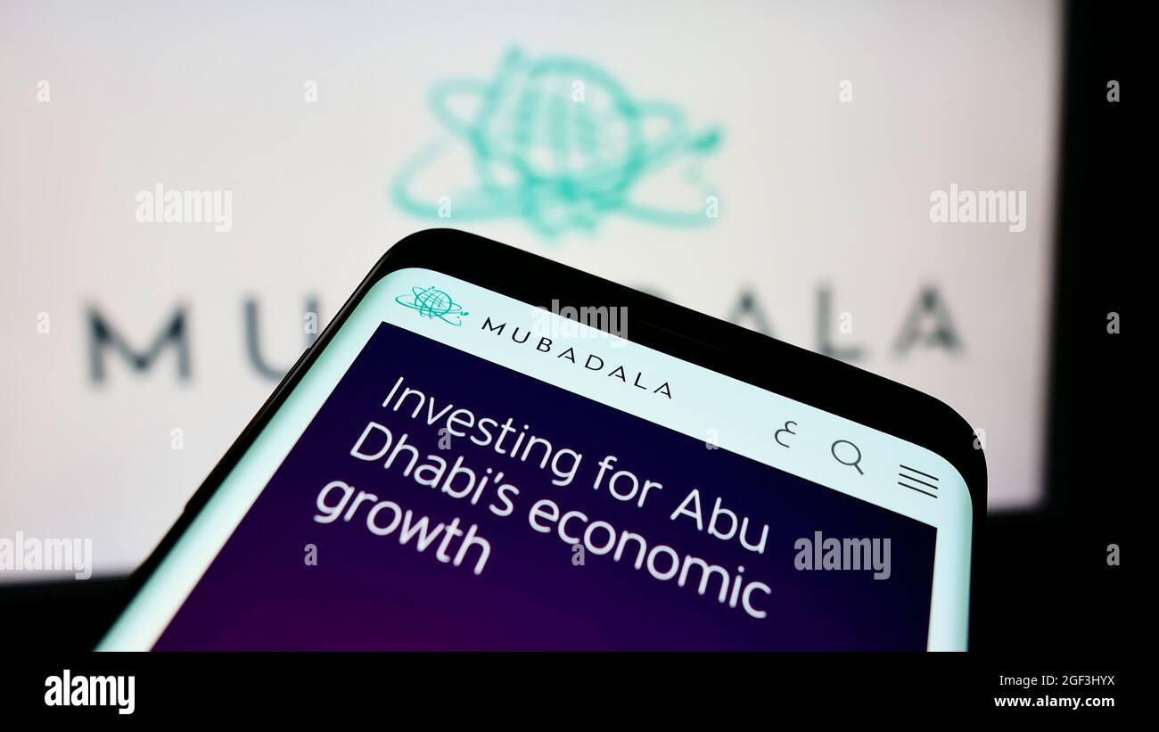 Teléfono móvil con página web del inversor de Emirati Mubadala Investment Company PJSC en la pantalla frente al logotipo. Enfoque en la parte superior izquierda de la pantalla del teléfono. Foto de stock