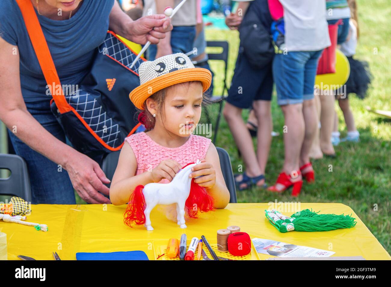 Zaporizhia, Ucrania - 19 de junio de 2021: Festival de la Familia de Caridad: Niña jugando con el caballo de juguete en el taller de arte y artesanía al aire libre Foto de stock