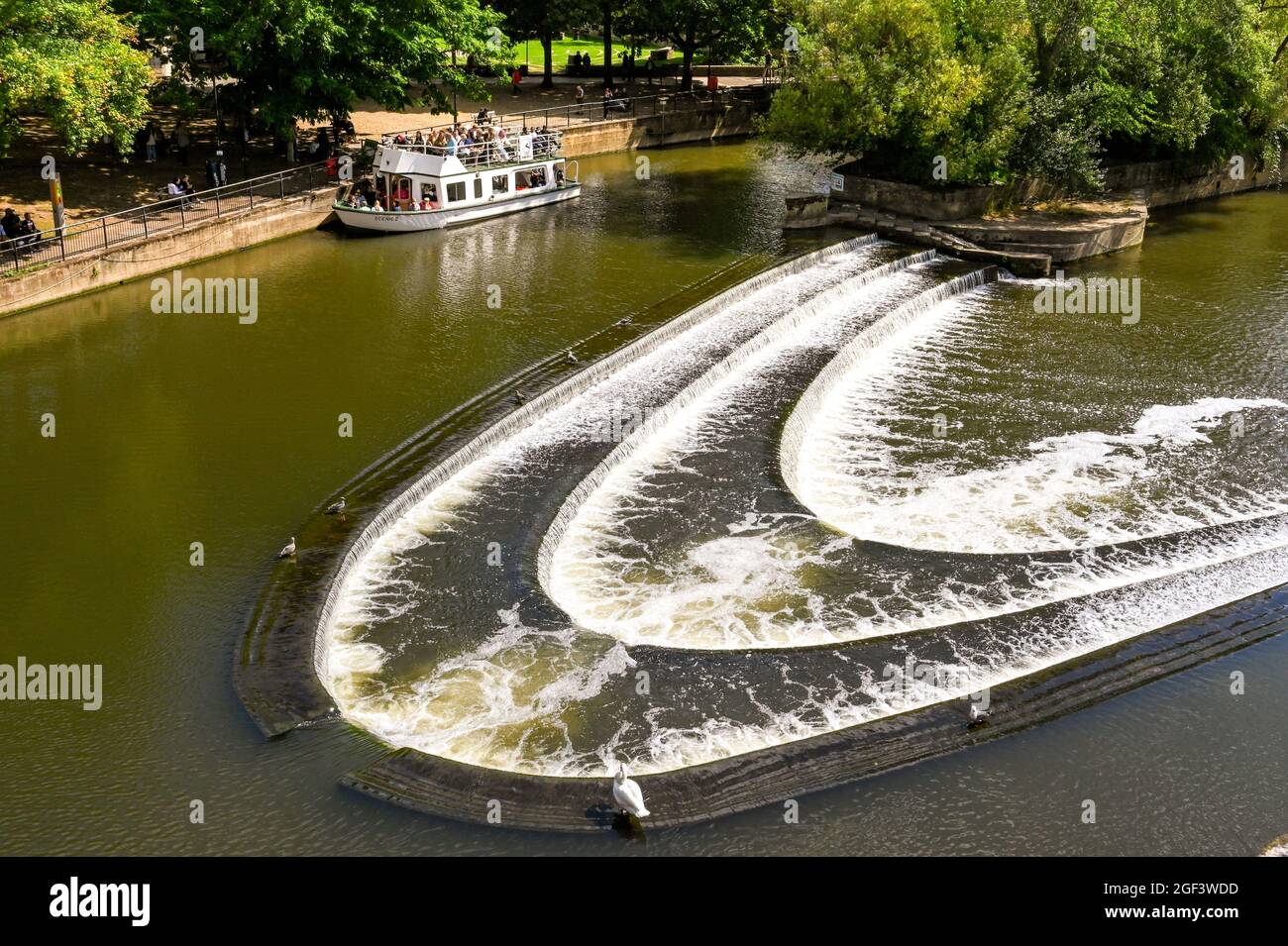 Bath, Inglaterra - 2021 de agosto: Weir en forma de herradura en el puente Pultney en el centro de Bath. En el fondo es un barco turístico Foto de stock