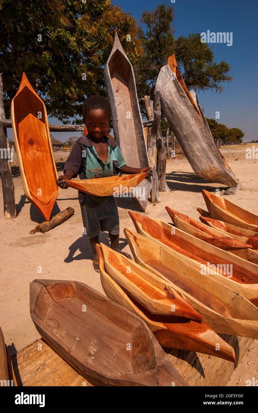 Niño pequeño africano que muestra una variedad de mini botes de mokoro para la venta como souvenirs para los turistas, Caprivi Strip, Namibia Foto de stock