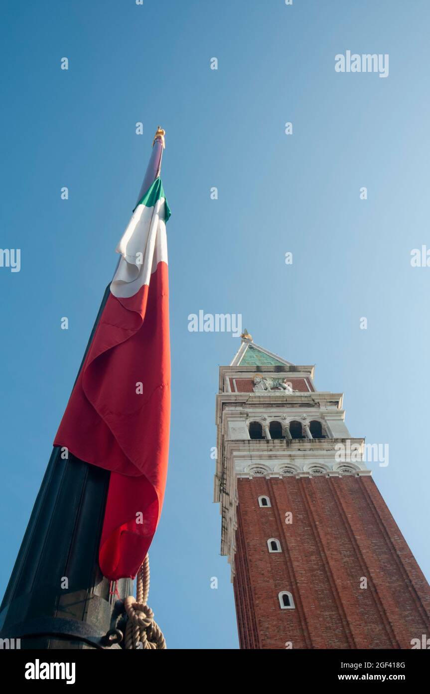 Vista vertical desde la parte inferior del campanario en la Plaza de San Marcos en Venecia y una bandera italiana Foto de stock