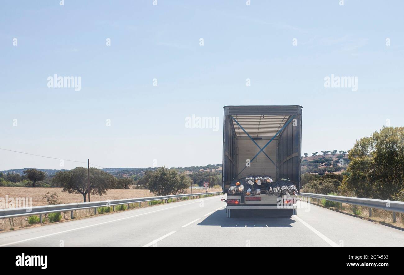Conducir detrás de los materiales de construcción camión cargado con barras de estructura de acero. Concepto de restricciones de longitud de carga sobredimensionada. Foto de stock