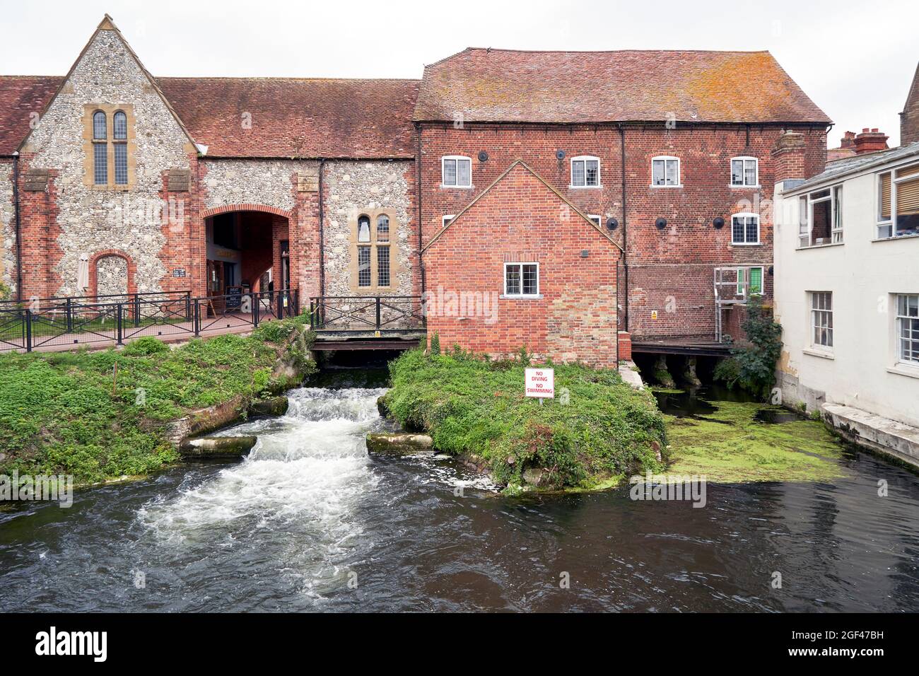 Antiguo molino en Salisbury Reino Unido construido de ladrillo rojo y una sección más antigua de piedra con el río Avon que fluye por debajo de él Foto de stock