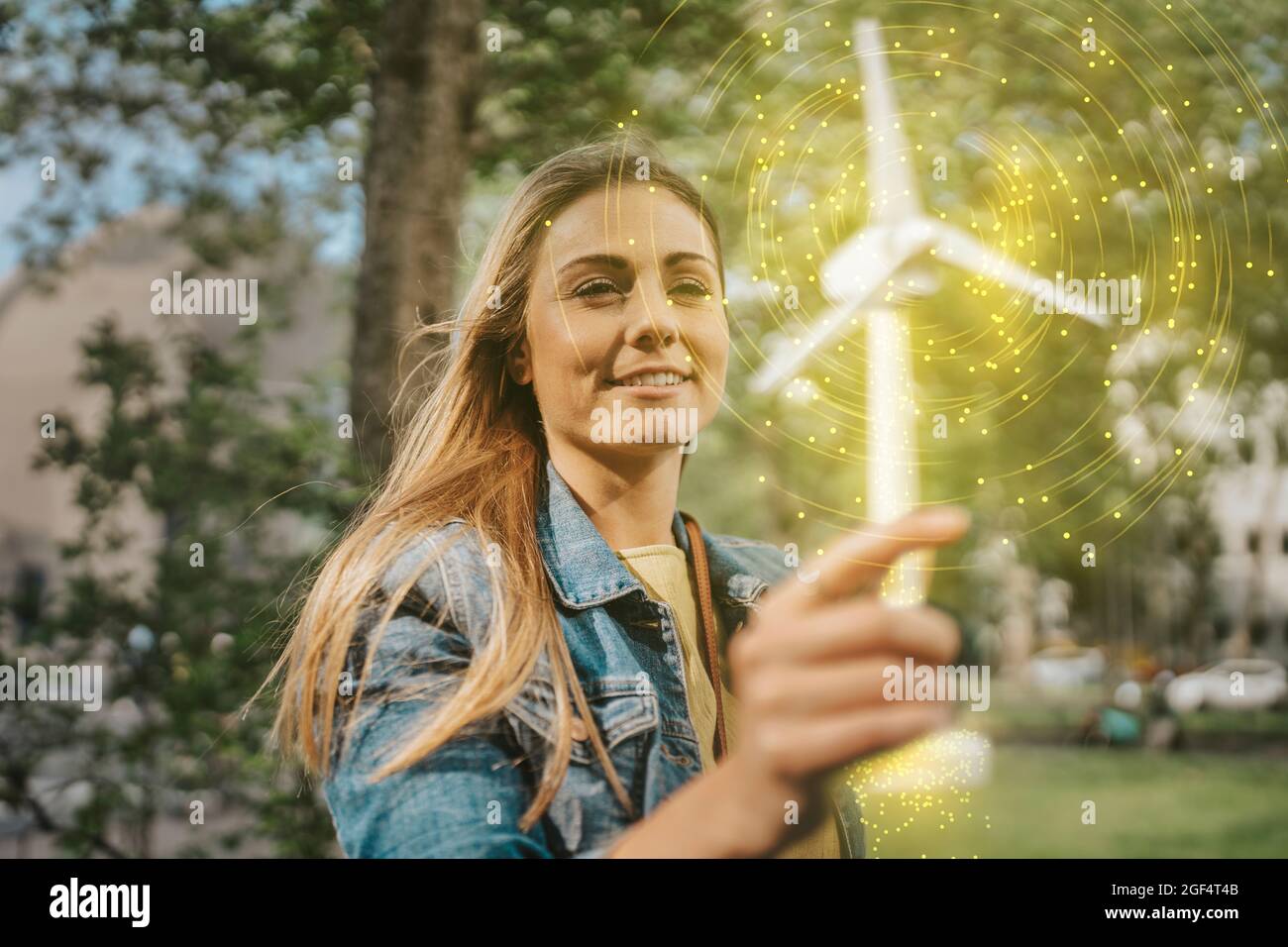 Mujer sosteniendo modelo de molino de viento brillante Foto de stock