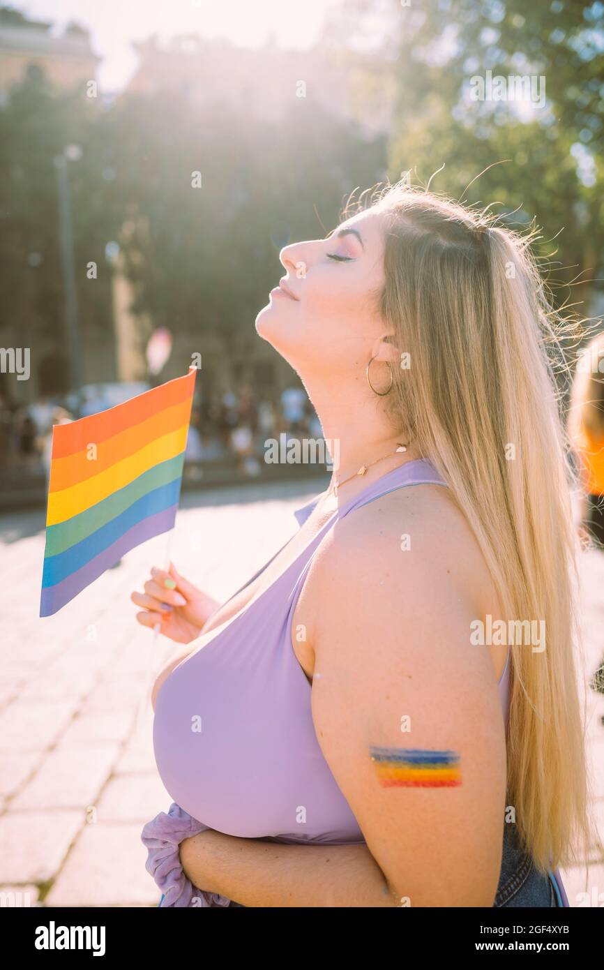 Mujer activista con bandera arcoiris el día soleado Foto de stock