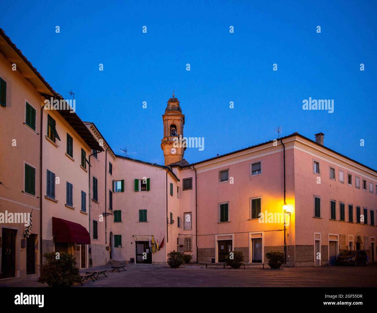 Italia, Provincia de Pisa, Pomarance, Piazza de Larderel al atardecer con el campanario de la Iglesia de San Giovanni Battista en el fondo Foto de stock