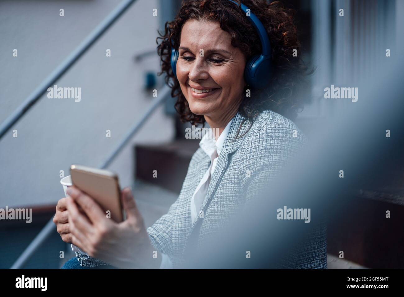 Mujer de negocios sonriente hablando durante la videoconferencia a través del teléfono móvil en la escalera Foto de stock
