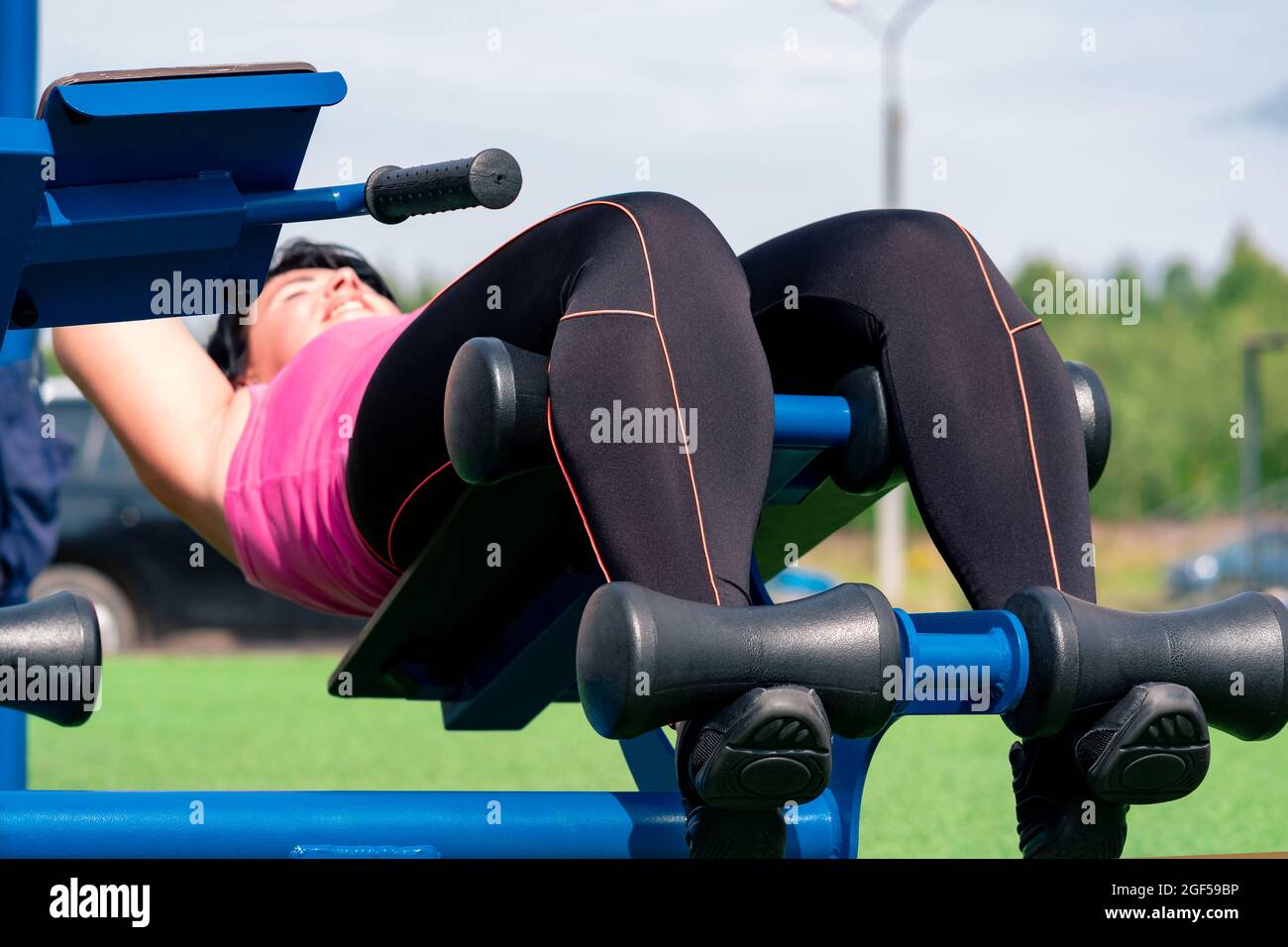 mujer joven realizando ejercicios abdominales utilizando una máquina de  ejercicios al aire libre de banco de sentarse Fotografía de stock - Alamy