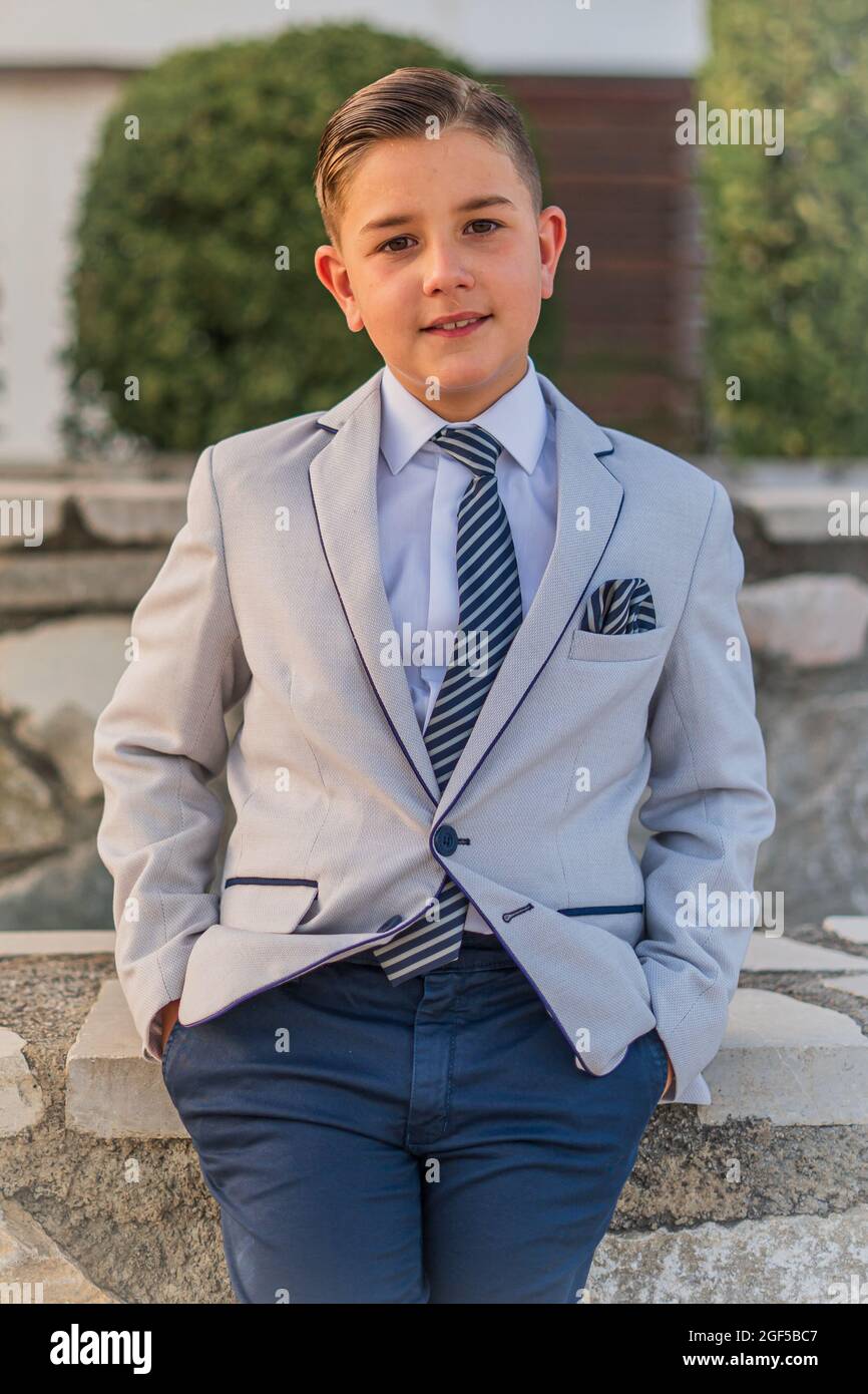 Tiro vertical de un adorable ni o en un traje formal posando