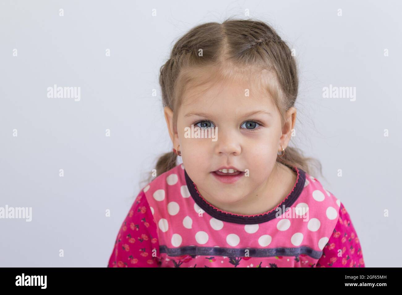 Retrato de un niño caucásico de tres años mirando la cámara con ojos brillantes sobre fondo blanco Foto de stock