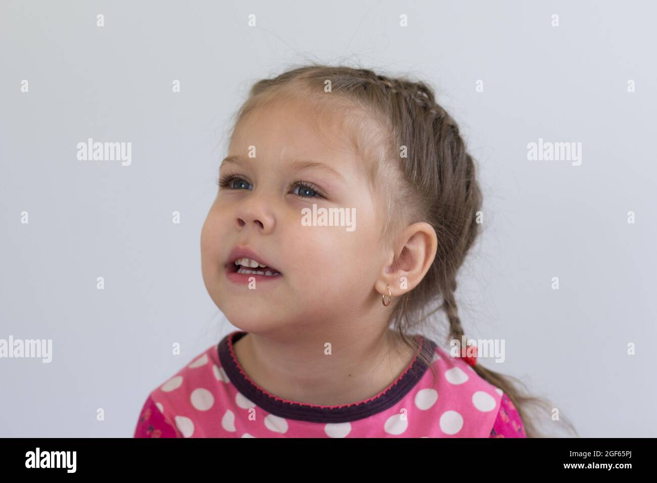 Retrato de un niño caucásico de tres años mirando a un lado con una mirada atenta sobre fondo blanco Foto de stock