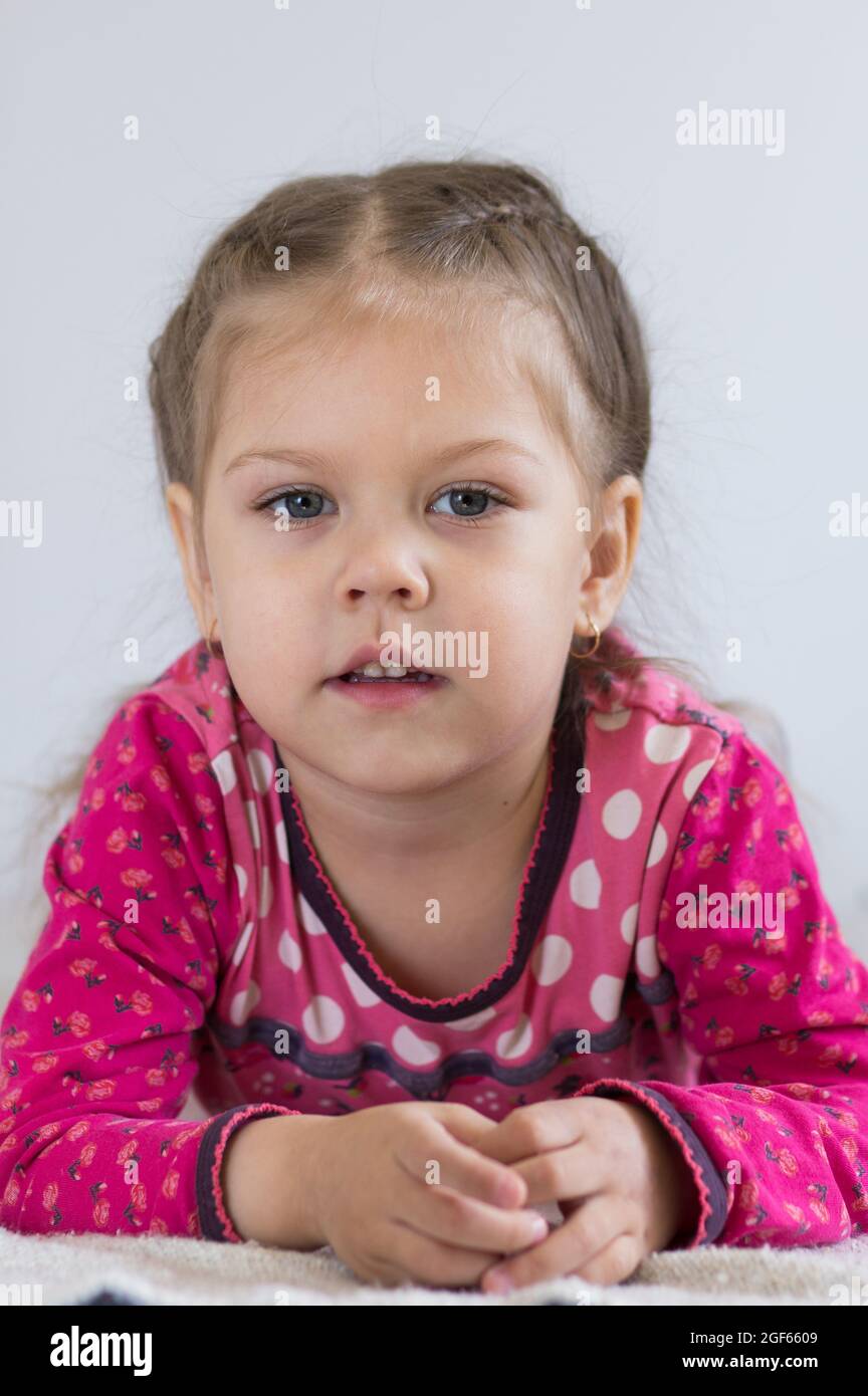 Retrato de un niño caucásico de tres años con mirada tranquila mirando la cámara sobre el fondo blanco Foto de stock