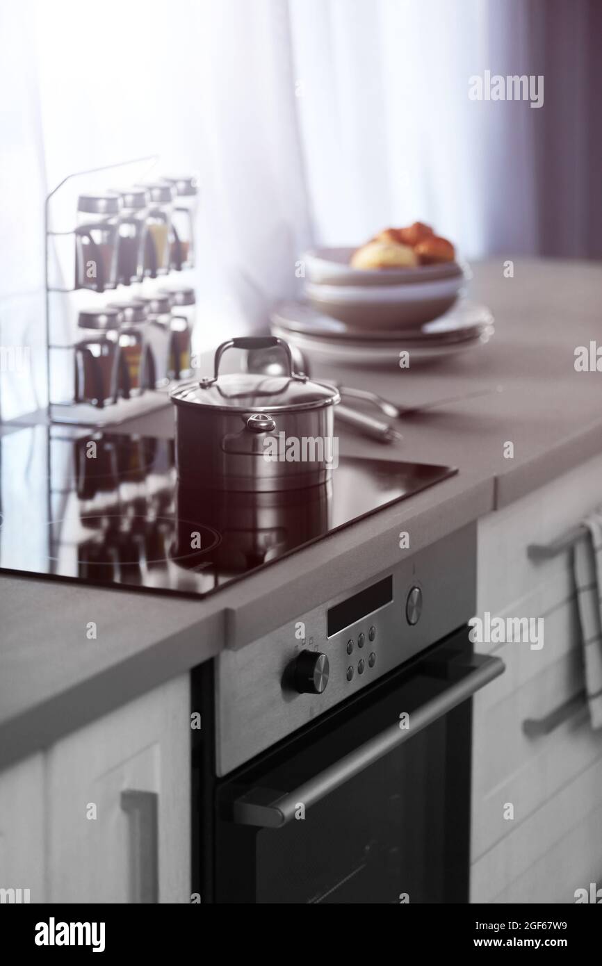 Mesa de cocina moderna con fogones eléctricos, utensilios de cocina y  especias junto a la ventana Fotografía de stock - Alamy