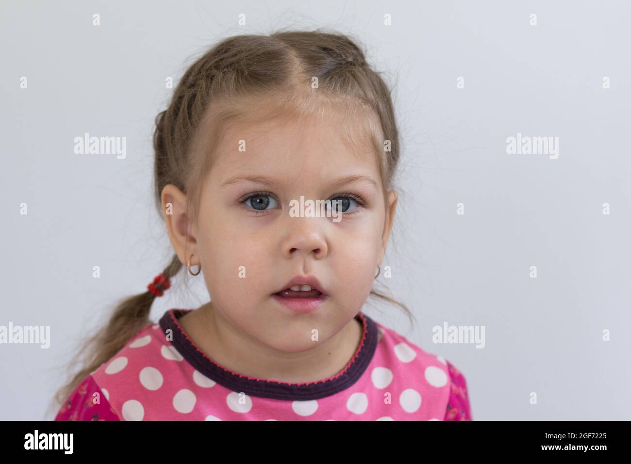 Retrato de un niño caucásico de tres años de edad con cara tranquila mirando la cámara sobre fondo blanco Foto de stock