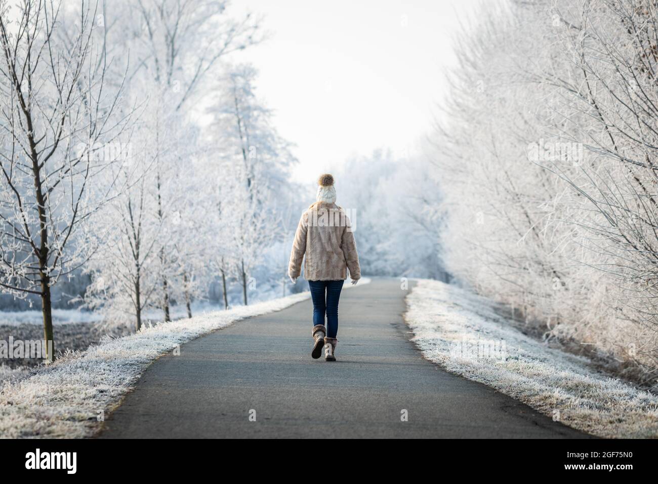 Mujer caminando por el camino en el parque en invierno. Relajación