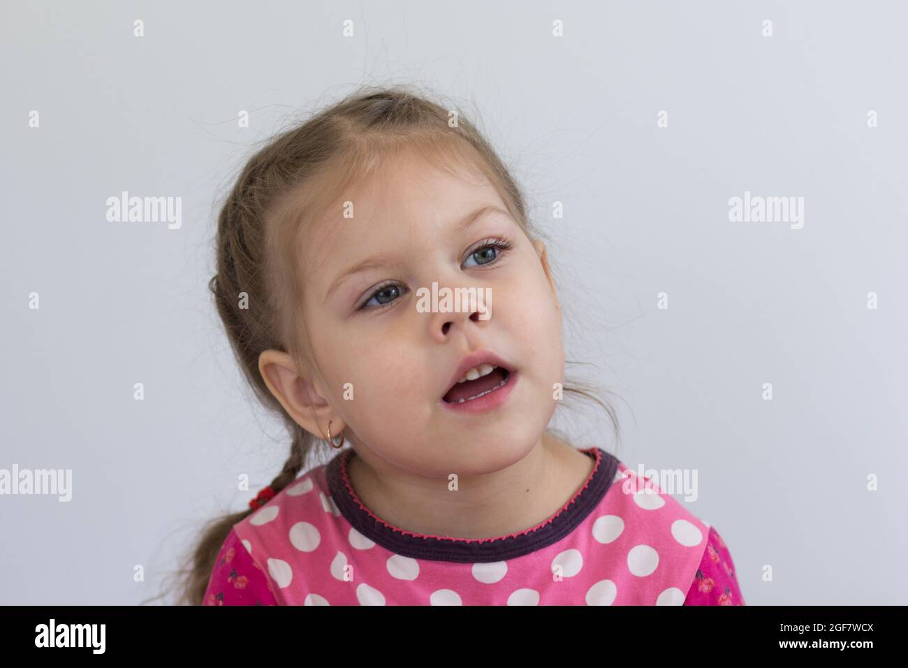 Retrato de un niño caucásico de tres años mirando a un lado con una mirada atenta sobre fondo blanco Foto de stock