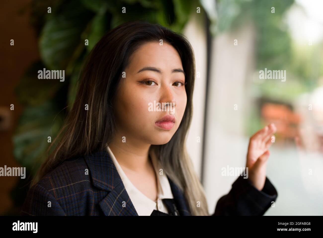 Mujer joven asiática Trabajadora de oficina / Científico de datos mirando hacia fuera ventana Foto de stock