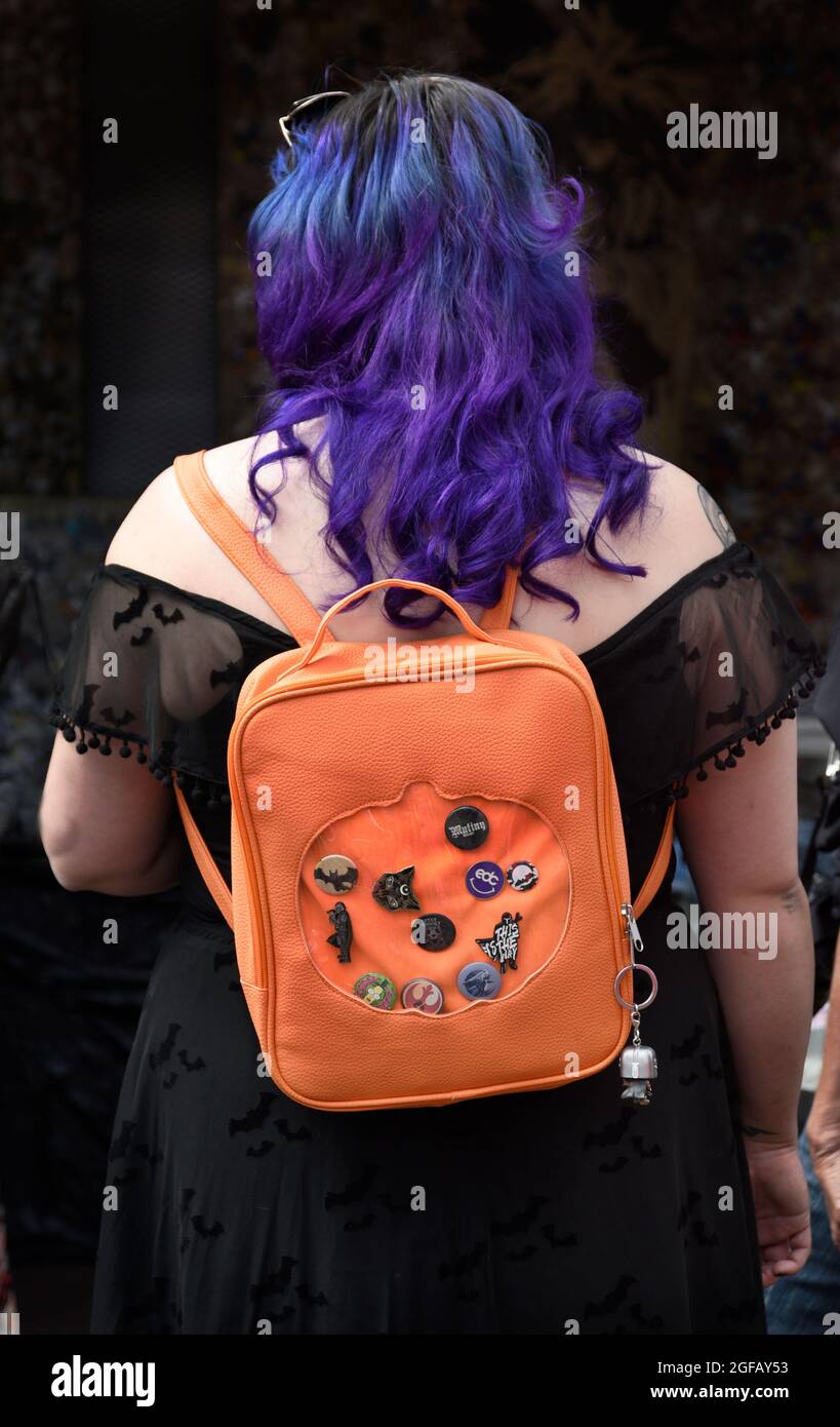 Una mujer con pelo púrpura con una mochila naranja adornada con una  variedad de insignias de mochila en Santa Fe, Nuevo México Fotografía de  stock - Alamy