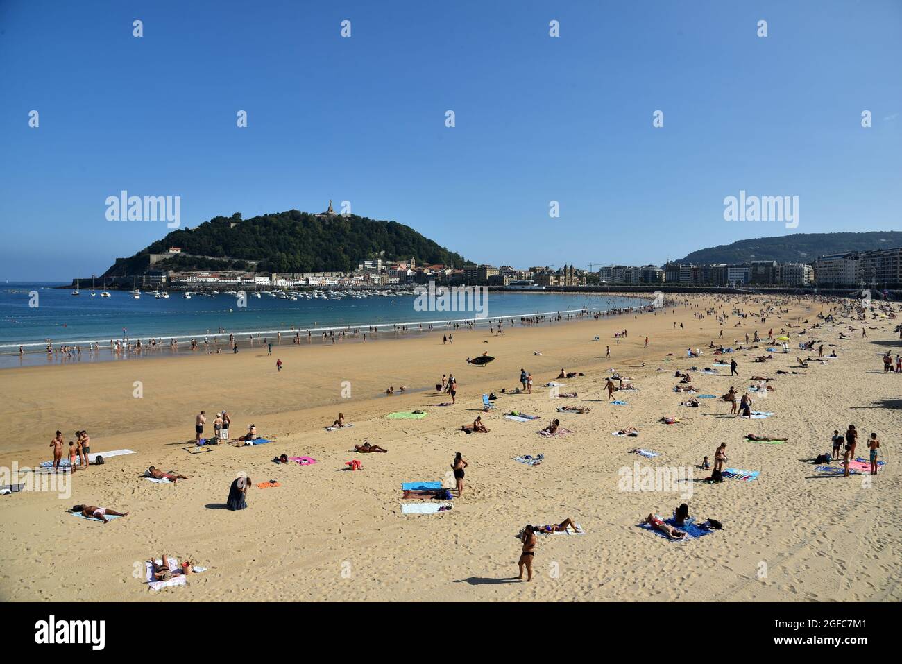 San Sebastián, Gipuzkoa, España. 5th de agosto de 2021. La gente se relaja en la playa de la Concha con el monte Urgull al fondo en San Sebastián Guipuzkoa España.La playa de la Concha es una de las mejores zonas turísticas de San SebastiÃn. Situado en el corazón de la ciudad, ofrece al visitante la oportunidad de disfrutar de magníficas vistas, como la que ofrece la bahía en forma de concha marina con la isla de Santa Clara en el centro, y a los lados de las montañas Urgull e Igeldo. (Imagen de crédito: © Ramon Costa/SOPA Images via ZUMA Press Wire) Foto de stock