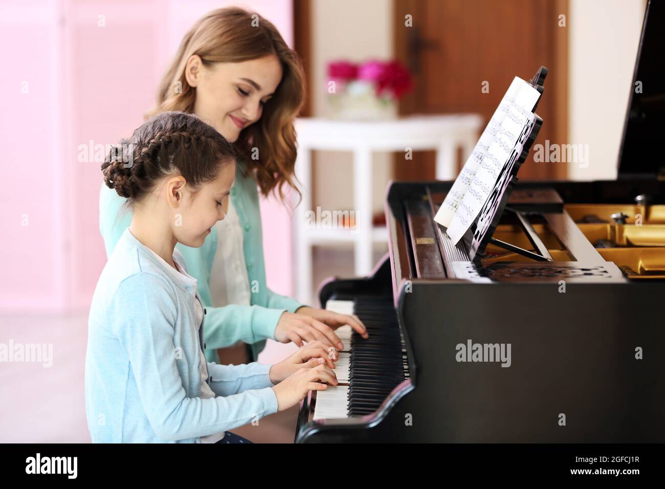 Niña pequeña aprendiendo tocar el piano con la maestra Fotografía de stock  - Alamy