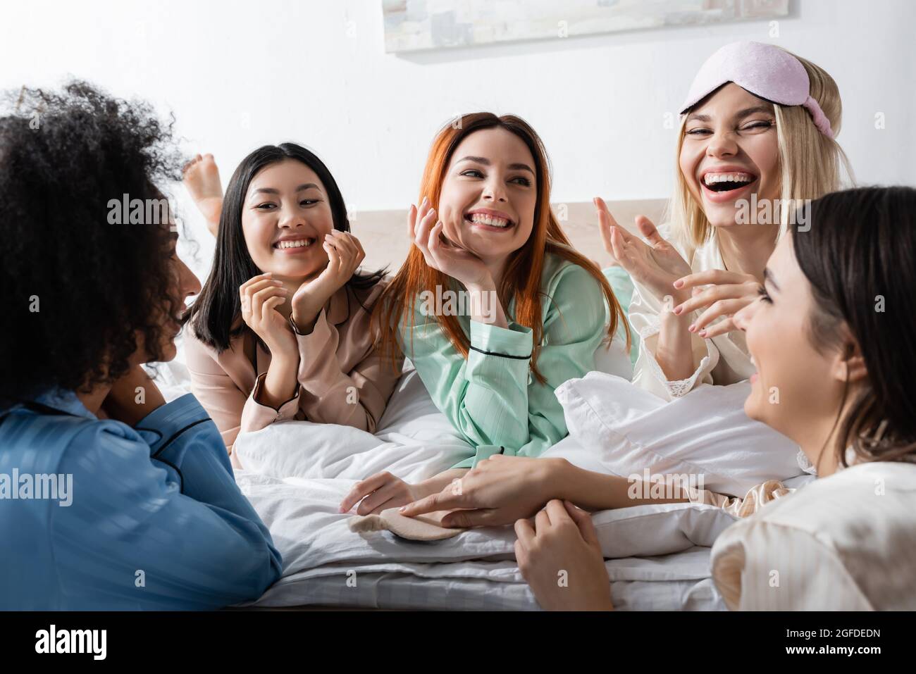 grupo de mujeres multiétnicas felices hablando y riendo durante la fiesta de sueño Foto de stock