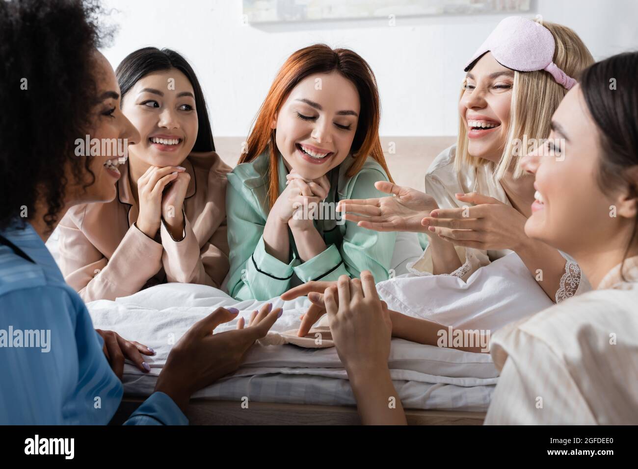 grupo de mujeres multiétnicas alegres hablando y riendo durante la fiesta de sueño Foto de stock