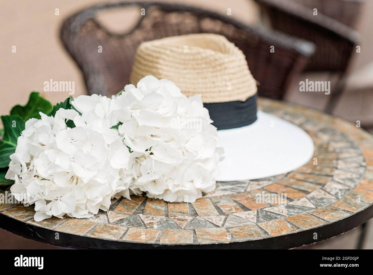 Sombrero solitario y flores de hortensias blancas sobre una mesa de piedra. Primavera romántica y verano de fondo. Enfoque selectivo suave. Foto de stock