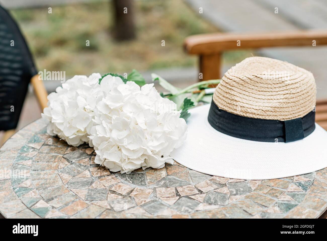 Sombrero solitario y flores de hortensias blancas sobre una mesa de piedra. Primavera romántica y verano de fondo. Enfoque selectivo suave. Foto de stock