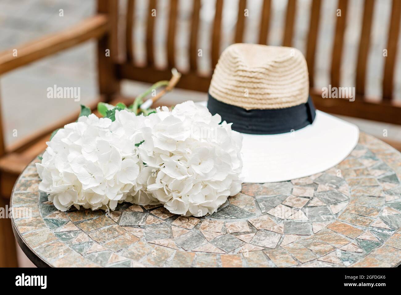 Sombrero solitario y flores de hortensias blancas sobre una mesa de piedra. Primavera romántica y verano de fondo. Enfoque selectivo suave. Foto de stock