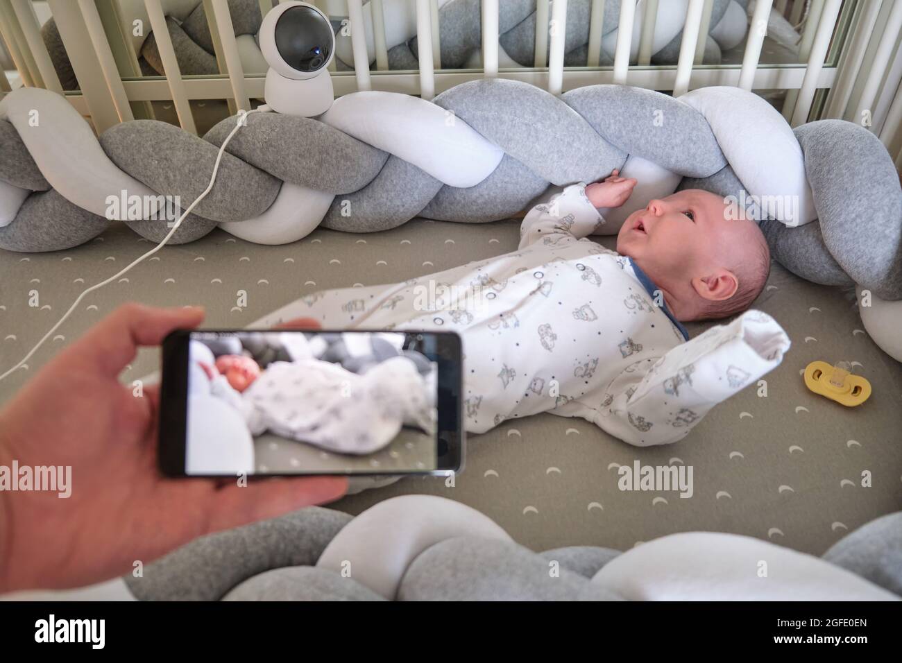 Vigilancia de un bebé recién nacido en una cuna a través de una cámara de  seguridad en línea y el Internet en un teléfono móvil Fotografía de stock -  Alamy